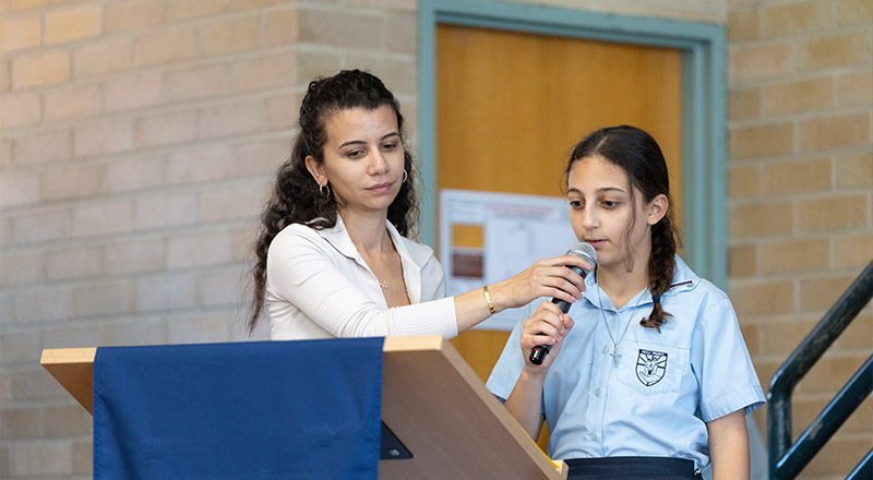 Teacher assisting Holy Family East Granville student in public speaking